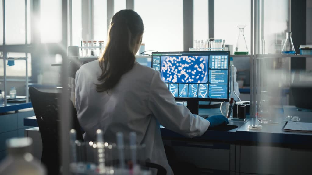 Medical Science Laboratory with Diverse Team of Professional Biotechnology Scientists Developing Drugs, Female Biochemist Working on Computer Showing Gene Therapy Interface. Back view Shot Researchers at UCLA have discovered new risk genes for PSP