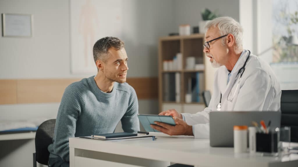 Experienced Middle Aged Family Doctor Showing Analysis Results on Tablet Computer to Male Patient During Consultation in a Health Clinic. Physician Sitting Behind a Desk in Hospital Office. Panelists at the International Dementia Conference called for increased funding and training for specialized dementia care